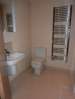 Bathroom with beige fllor tiles white utilities and chrome towel radiator