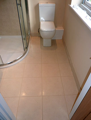 Ensuite bathroom with beige wall and floor tiles white utilities