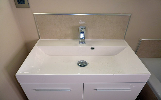 White modern bathroom sink with beige tiles and aluminium trim