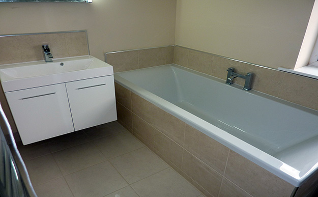 Ensuite Bathroom with beige tiles on floor, bath panel , bath splash-back and sink splash-back.